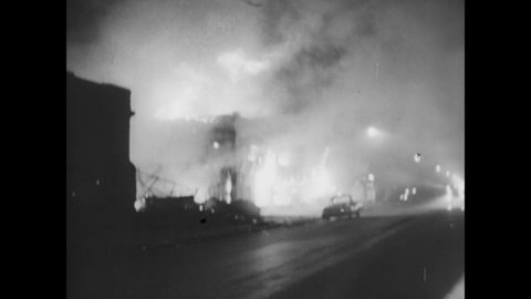 CIRCA 1967 - Firemen work to put out burning buildings at night during race riots in Detroit, Michigan.