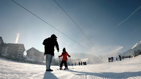Bansko, Bulgaria - 22 Feb, 2019: Winter ski resort Bansko, people take ski lessons under gondola cable car, slow motion