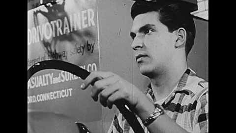 CIRCA 1950s - Drivers ed students take a written exam and simulator exam.