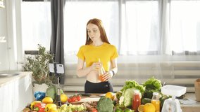 Cute dietitian blogger writes video content about healthy food and healthy eating on her smartphone in her kitchen