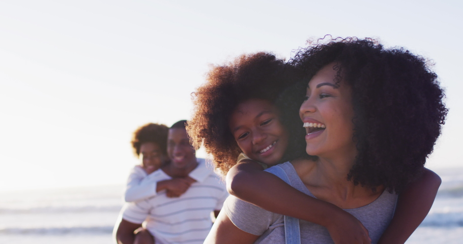 African american mother and father giving a piggyback ride to their daughter and son at the beach. family travel vacation leisure concept Royalty-Free Stock Footage #1071447667