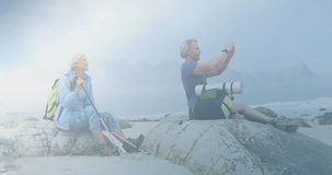 Caucasian senior couple hiking, taking photo with smartphone, over clouds and network of connections. active lifestyle, healthy retirement and global communication concept digitally generated video.