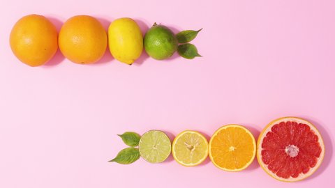 6k Whole and half citrus fruits ordered in line with green leaves move on pastel pink background. Stop motion