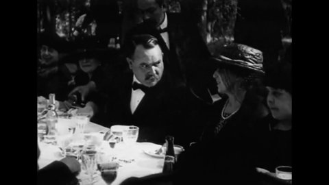 CIRCA 1920 - Wealthy bankers and aristocrats attend a fancy outdoor luncheon.