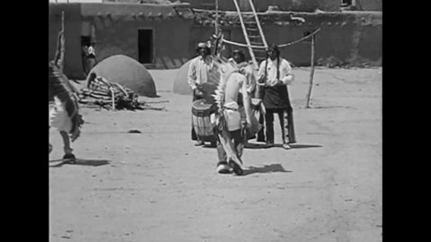 CIRCA 1919 - Native Americans dance in feathered costumes to drummers in Santa Fe, New Mexico.