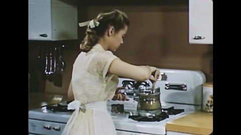 CIRCA 1950 - A woman helps her teenage daughter prepare tuna melts and snacks for her friends.