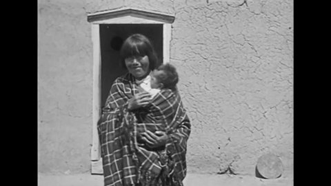 CIRCA 1919 - Native Americans in Santa Fe, New Mexico wear feathered costumes and a mother proudly shows off her baby.