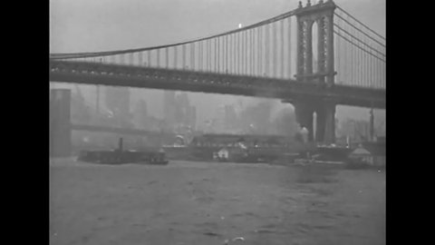CIRCA 1919 - A boat passes under the Brooklyn Bridge and cruises past other structures.