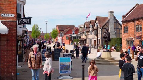 William Shakespeare's Statue in Stratford-upon-Avon. People walk on a sunny day and buy ice cream in the center of the old town. April 24, UK 2021