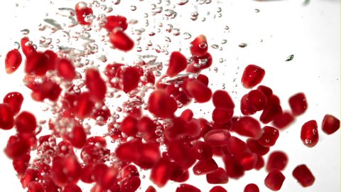 Super slow motion pomegranate grains fall under the water with air bubbles. On a white background.Filmed on a high-speed camera at 1000 fps. High quality FullHD footage