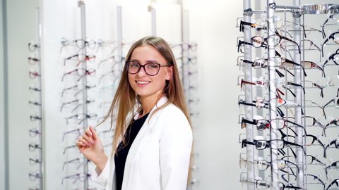 KYIV, UKRAINE - August 2020: Portrait of a smiling woman at optics. Fashionable lady in new eyeglasses on the background of optical store. Lovely female choosing spectacles.