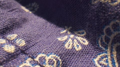 Extreme close-up over blue and white paisley patterned fabric.