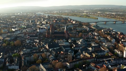 full drone shot of the red Cathedral church of Mainz in the middle of the old town and tiny houses with the Rhine river in the back in Germany