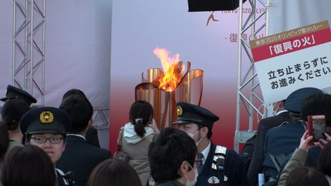 SENDAI, MIYAGI, JAPAN - 21 MARCH 2020 : Olympic Flame displayed at Sendai station. Crowd of people wearing masks. Tokyo Olympic 2020 have been postponed to 2021 due to Coronavirus (COVID-19).
