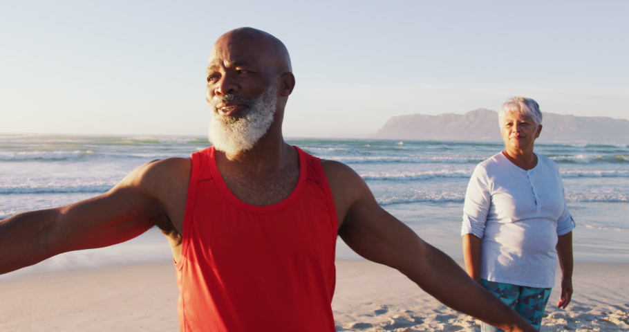 Senior african american couple practising yoga at the beach. healthy outdoor leisure time by the sea. Royalty-Free Stock Footage #1071480253