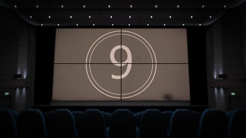 Countdown film on the cinema screen in the movie theater. Camera zooming to projection screen with entertainment presentation in the dark cinema hall interior without audience, template 3d animation.