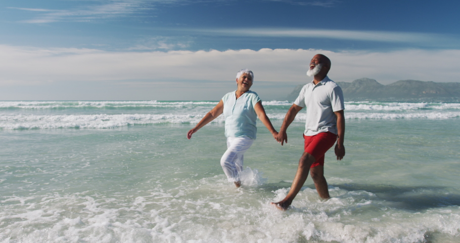 Senior african american couple walking and holding hands at the beach. healthy outdoor leisure time by the sea. | Shutterstock HD Video #1071485350