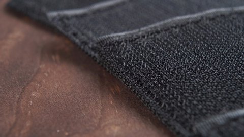Black textured Velcro with fabric fastening tapes. Close-up. Dark wooden background. Macro. Dolly Shot