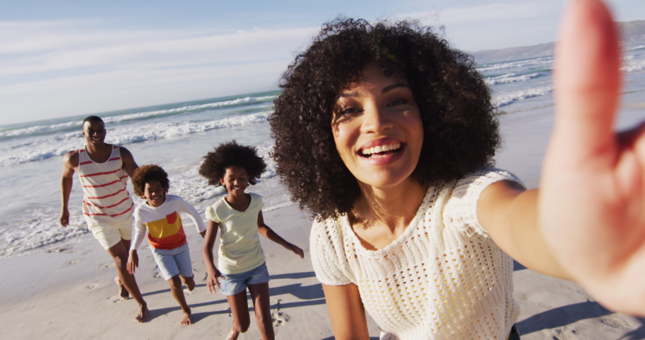 Smiling african american parents and their children taking a selfie with smartphone on the beach. family outdoor leisure time by the sea. Royalty-Free Stock Footage #1071494662