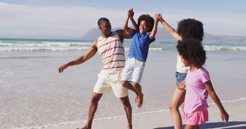 Smiling african american parents and their children walking and holding hands on the beach. family outdoor leisure time by the sea.