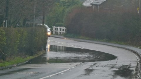 St Helens , Merseyside , United Kingdom (UK) - 02 23 2020: Vehicles driving along rainy stormy flash flooded road corner bend UK