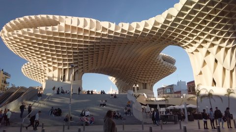 Seville , Spain - 02 02 2020: Real Time Static Shot of people hanging out at Las Setas monument, a landmark wooden structure also known as Metropol Parasol, in downtown Seville, Spain.