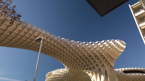 Seville , Spain - 02 02 2020: High to low tilt down shot of Las Setas, a landmark wooden structure also known as Metropol Parasol, in downtown, Seville, Spain, on a sunny day.