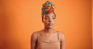 Surprised black girl in the video. African woman with orange turban on orange background.