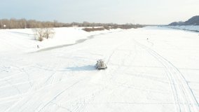 Aerial video: a hovercraft rides a frozen river across ice and snow