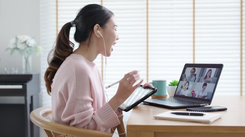 Back view of business woman talking about sale report in video conference. Asian team using laptop and tablet online meeting in video call.Working from home, Working remotely and Social isolation.