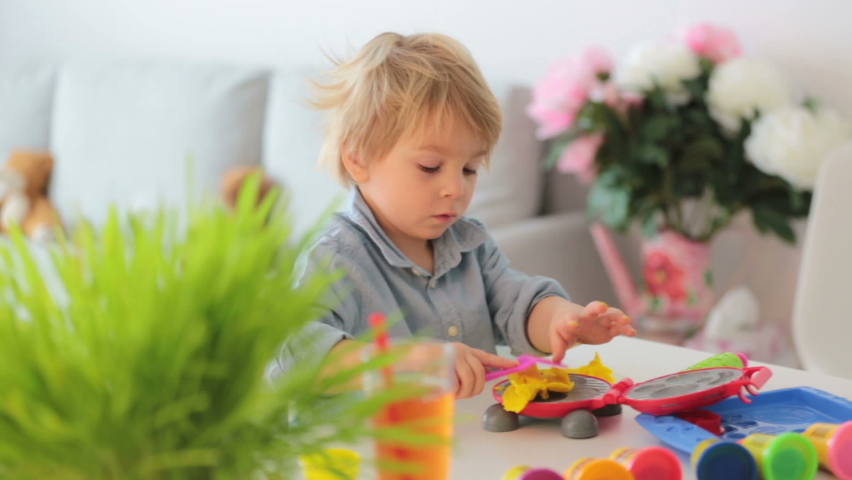 Cute blond child,  sweet boy, playing with play doh modeline at home, making different objects