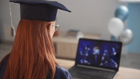 remote education, female student in an academic gown and hat receives a diploma at an online ceremony with male teacher in medical mask via video link on laptop