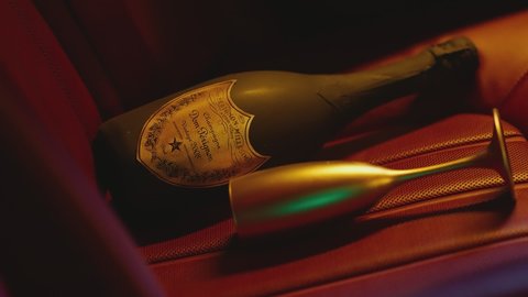 Golden cup , bottle of champagne . Studio shot of beautiful car interior with golden bottle of sparkle wine .  Gold bottle of Dom Perignon champagne on rear car seat. Expensive and luxury composition 