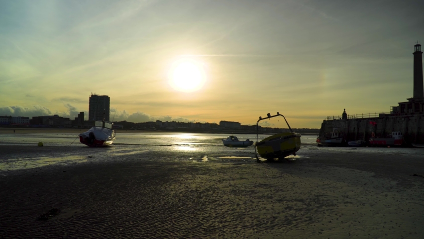 Silhouette of a harbour with boats on the beach during sunset golden hour