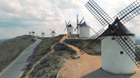 Consuegra, Spain - April 21, 2021: Aerial view, tourists visiting famous windmills in Consuegra town, symbol of Castilla-La Mancha, some windmills still work since their manufacture. Heritage concept