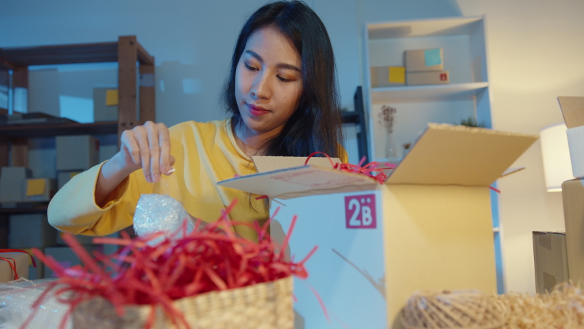 Young Asia woman packing box parcel use paper for support product easy damage fragile product in home office at night. Small business owner, online market delivery, lifestyle freelance concept. Royalty-Free Stock Footage #1071531541
