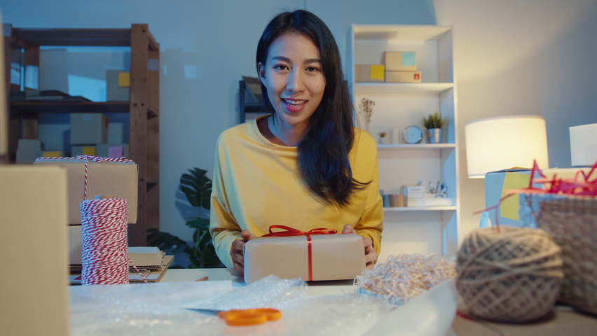 Happy young Asia businesswoman looking at camera selling  introduce product to client video live streaming in online shop  marketplace at night. Small business owner, online market delivery concept. Royalty-Free Stock Footage #1071531550