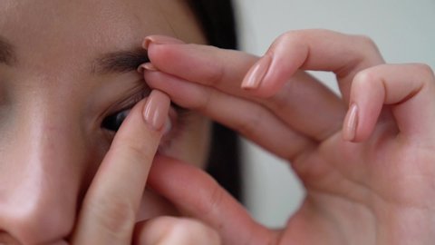 Closeup female portrait, hand is holding contact lenses. Woman is removing soft silicone optical lens from eye. Vision correction of myopia, hyperopia, astigmatism concept. Ophthalmic diseases.
