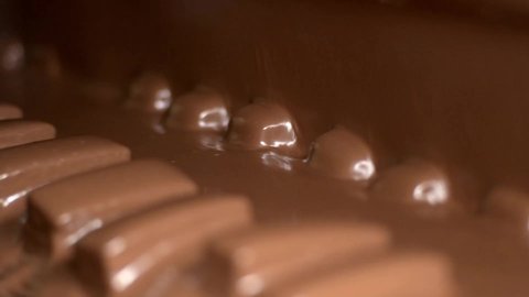 It is poured over the cakes with chocolate. Nougat and peanut chocolate production. The chocolate bars move along the conveyor belt in the confectionery factory for confectionery production. 