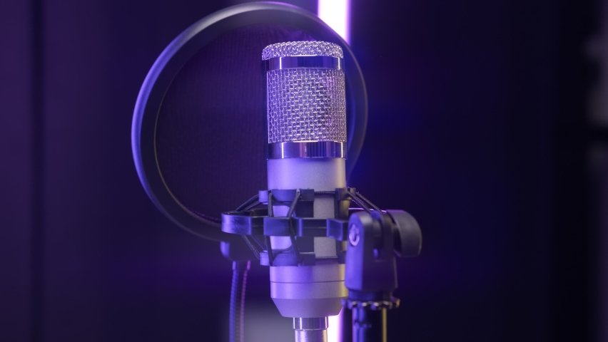 Studio recording, professional microphone in recording studio, close-up. Shooting professional microphone for dubbing and singing in recording studio in rays of colorful floodlights. podcast concept. Royalty-Free Stock Footage #1071535150
