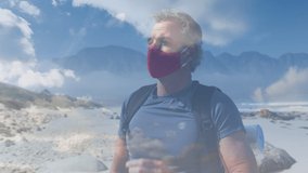 Caucasian senior man wearing face mask hiking by the coast over fast moving clouds. active outdoor retirement lifestyle during coronavirus covide 19 pandemic concept digitally generated video.