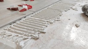 A worker is leveling the ceramic tile with wedges and clips. Tile leveling system