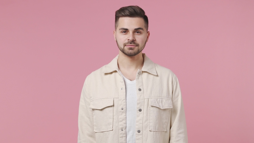 Handsome brunet caucasian young man 20s wears light jacket white t-shirt posing look camera aside charming smile isolated on pastel pink wall color background studio portrait People lifestyle concept Royalty-Free Stock Footage #1071544732