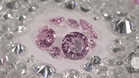 A group of pink diamonds arranged in the middle of white diamonds in a white background.Top view of pink diamonds. white diamonds background video 4K.
