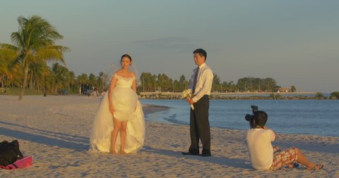 MIAMI, NOVEMBER 2014: Bride and groom taking pictures on Miami Beach seaside at sunset, Florida, USA
