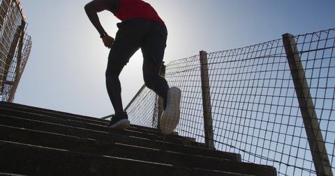 Focused african american man running up the stairs, exercising outdoors on sunny day. fitness, healthy and active lifestyle concept.