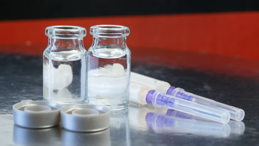 bottles in vaccine and syringes with a vaccine on background of the Germany flag, vaccine against coronavirus covid-19, closeup, a Healthcare Video by LanKS