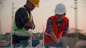 Asian engineer, foreman or leader discussion about home solar cell farm and wind turbine model in construction site project and High voltage power line pylon at sunset. Teamwork, Leadership concept - Powered by Shutterstock - Get 15% off with code: PIKWIZARD15