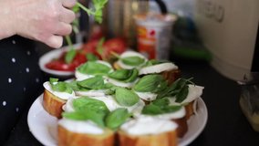 Video of the hands of a person adding fresh green leaves to a bread and cheese dish