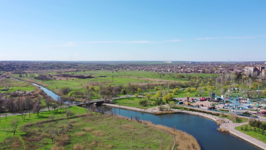 Small river in the city. Amusement park on the river bank. View from above. Spring time of the year